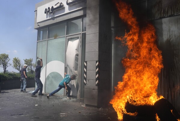 FILE - Protesters smash windows and burn tires at Bank Audi during a protest demanding the release of depositors' trapped savings, in Beirut, Lebanon, Thursday, June 15, 2023. Without reforms, Lebanon will continue to see triple-digit inflation, and public debt in the small, crisis-ridden country could reach nearly 550% of GDP by 2027, the International Monetary Fund warned in a report Thursday, June 29. (AP Photo/Hussein Malla, File)