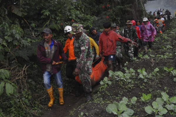 Rescuers carry the body of a victim of the eruption of Mount Marapi in Batu Palano, West Sumatra, Indonesia, Tuesday, Dec. 5, 2023. Rescuers searching the hazardous slopes of the volcano found more bodies of climbers who were caught by a surprise weekend eruption, raising the number of confirmed dead, officials said Tuesday. (AP Photo/Ardhy Fernando)