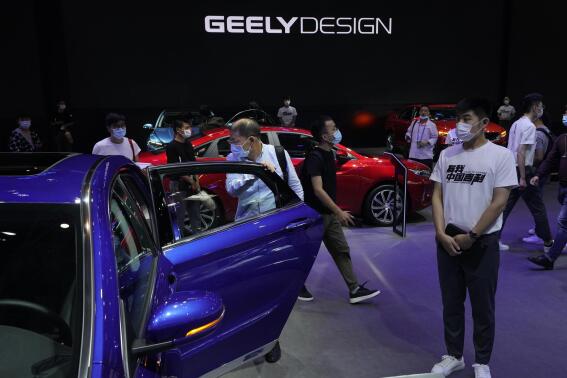 FILE - Visitors look at cars produced by Geely at the Auto China 2020 show in Beijing on Sept. 27, 2020. Renault SA and China's Geely announced plans Tuesday, Nov. 8, 2022 for a jointly owned venture to produce gasoline-powered and hybrid powertrains, adding to a series of partnerships between global automakers to share soaring technology costs. (AP Photo/Ng Han Guan, File)