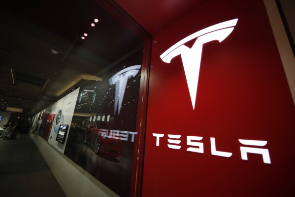FILE - A sign bearing the Tesla company logo is displayed outside a Tesla store in Cherry Creek Mall in Denver, Feb. 9, 2019. Mohegan Sun, a casino and entertainment complex in Connecticut owned by the federally recognized Mohegan Tribe, announced on Wednesday, July 26, 2023, that Tesla will open a showroom with a sales and delivery center this fall on its sovereign property. By doing so, it circumvents laws in states that bar vehicle manufacturers from also being retailers in favor of the dealership model. (AP Photo/David Zalubowski, File)
