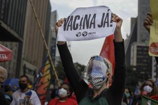 A demonstrator holds a sign that reads in Portuguese; "'Vaccine now", during a protest against Brazilian President Jair Bolsonaro and his handling of the COVID-19 pandemic on Paulista Avenue, in Sao Paulo, Brazil, Saturday, June 19, 2021. Brazil's COVID-19 death toll is expected to surpass the milestone of 500,000 deaths on Saturday night. (AP Photo/Marcelo Chello)