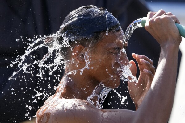A man pours water from a pipe over himself on a hot day in Manila, Philippines, Friday, April 26, 2024. (Ǻ Photo/Aaron Favila)