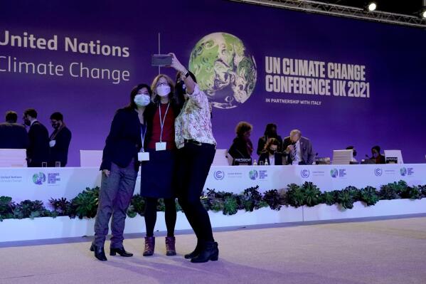 Delegates pose for a selfie together in the plenary room at the COP26 U.N. Climate Summit, in Glasgow, Scotland, Saturday, Nov. 13, 2021. Going into overtime, negotiators at U.N. climate talks in Glasgow are still trying to find common ground on phasing out coal, when nations need to update their emission-cutting pledges and, especially, on money. (AP Photo/Alberto Pezzali)