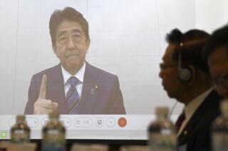Former Japanese Prime Minister Shinzo Abe, seen on a screen, during a meeting in Taipei, Wednesday Dec. 1, 2021. China lashed out at Shinzo Abe Wednesday, Dec. 1, 2021, after the former Japanese prime minister warned of the serious security and economic consequences of any Chinese military action against the self-ruled island. (Kyodo News via AP)