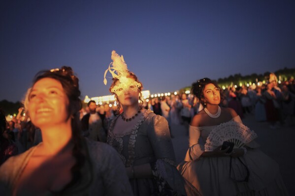 Costumed guests watch fireworks in the gardens of the Versailles castle before the Great Masked Ball in Versailles, outside Paris, Saturday, June 21, 2025. (AP Photo/Christophe Ena)