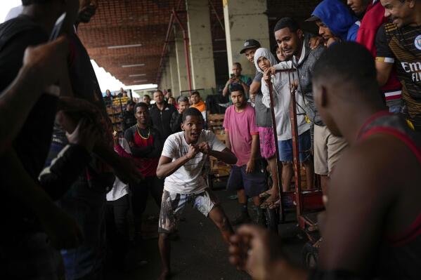 Cart pushers clench their fists threatening to start a fight after their carts accidentally colliding into each other at the Cease wholesale market in Rio de Janeiro, Brazil, Thursday, Sept. 29, 2022. (AP Photo/Matias Delacroix)