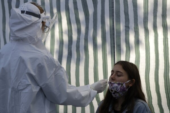 A woman gets tested for COVID-19 at a sampling station in Prague, Czech Republic, Monday, Sept. 21, 2020. The country coped well with the first wave of the coronavirus infections in the spring but has been facing a record surge of the new confirmed cases last week. (AP Photo/Petr David Josek)