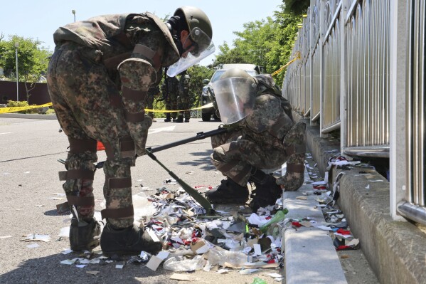 South Korean soldiers wearing protective gears check the trash from a balloon presumably sent by North Korea, in Incheon, South Korea, Sunday, June 2, 2024. North Korea launched hundreds of more trash-carrying balloons toward the South after a similar campaign a few days earlier, according to South Korea’s military, in what Pyongyang calls retaliation for activists flying anti-North Korean leaflets across the border. (Im Sun-suk/Yonhap via AP)