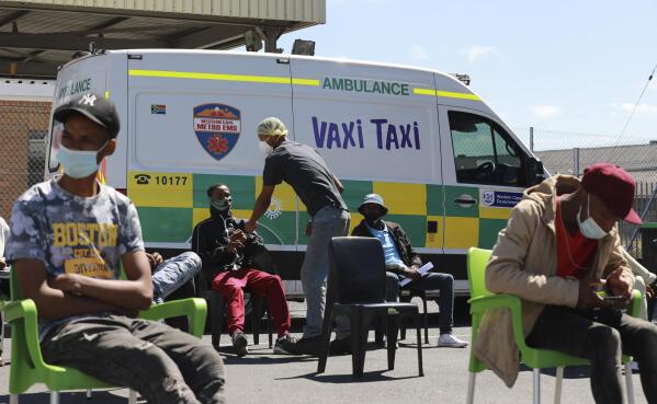 People wait to be vaccinated by a member of the Western Cape Metro EMS (Emergency Medical Services) at a mobile "Vaxi Taxi" which is an ambulance converted into a mobile COVID-19 vaccination site in Blackheath in Cape Town, South Africa, Tuesday, Dec. 14, 2021. The omicron variant appears to cause less severe disease than previous versions of the coronavirus, and the Pfizer vaccine seems to offer less defense against infection from it but still good protection from hospitalization, according to an analysis of data from South Africa, where the new variant is driving a surge in infections. (AP Photo/Nardus Engelbrecht)