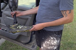 Farmer Joe Marszalkowski holds a prosthetic leg, Monday, July 27, 2020, that he found Sunday in a soybean field on his farm in West Addison, Vt. The leg was lost by double amputee Chris Marckres while skydiving on Saturday. (Jack Thurston/NECN and NBC10 Boston via AP)