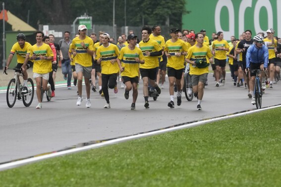 Formula One drivers run as they pay tribute to the late Formula One Brazilian driver Ayrton Senna at the Tamburello turn, at the Dino and Enzo Ferrari racetrack, in Imola, Italy, Thursday, April 16, 2024. The three-time F1 world champion died in a crash at the Imola race track in San Marino. (AP Photo/Luca Bruno)
