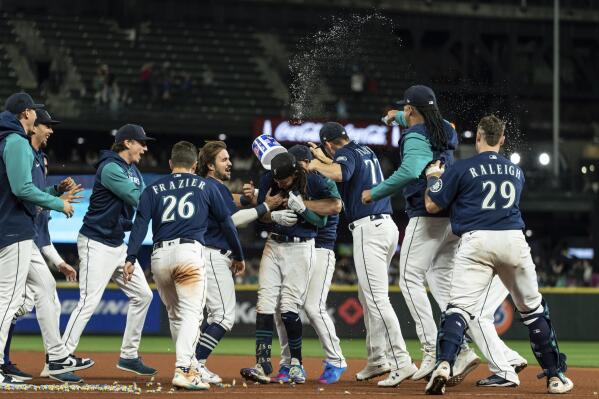 Seattle Mariners, including Adam Frazier (26), J.P. Crawford, center, Chris Flexen (77), Luis Castillo, second from right, and Cal Raleigh, right, celebrate after a single by Crawford in the 11th inning drove in the winning run in a baseball game against the Texas Rangers, Thursday, Sept. 29, 2022, in Seattle. The Mariners won 10-9. (AP Photo/Stephen Brashear)