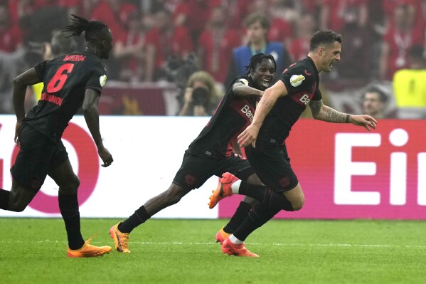 Leverkusen's Granit Xhaka, right, celebrates after scoring his side's opening goal during the German Soccer Cup final match between 1. FC Kaiserslautern and Bayer Leverkusen at the Olympic Stadium in Berlin, Germany, Saturday, May 25, 2024. (AP Photo/Matthias Schrader)