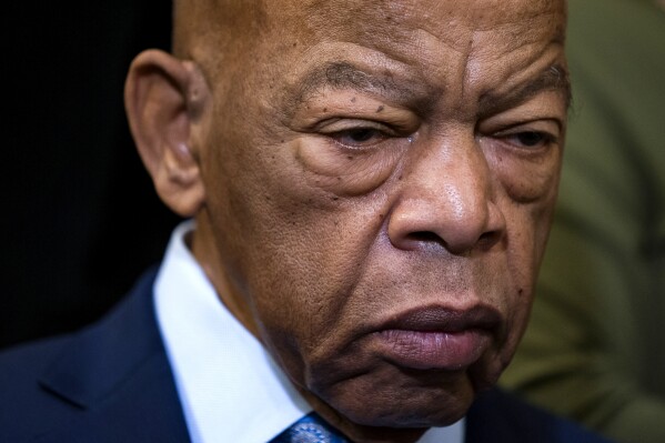FILE - In this Friday, Dec. 6, 2019, file photo, civil rights leader U.S. Rep. John Lewis, D-Ga., is extolled at an event with fellow Democrats before passing the Voting Rights Advancement Act to eliminate potential state and local voter suppression laws, at the Capitol in Washington. An upcoming biography of Lewis will draw upon hundreds of interviews, along with the civil rights activist's FBI files and materials from a planned book that was never completed. (AP Photo/J. Scott Applewhite, File)