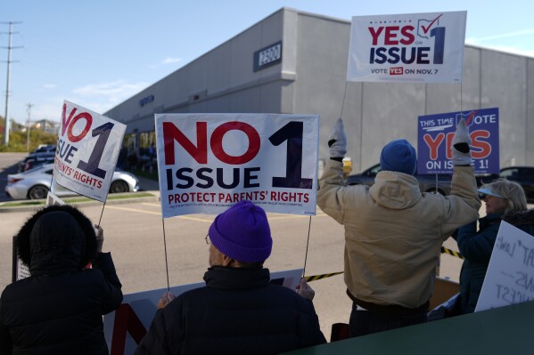 People gather in the parking lot of the Hamilton County Board of Elections as people arrive for early in-person voting, in Cincinnati, Thursday, Nov. 2, 2023. They urge people to vote for or against the measure known as Issue 1. Issue 1 is the only abortion question on any state ballot this year. (AP Photo/Carolyn Kaster)