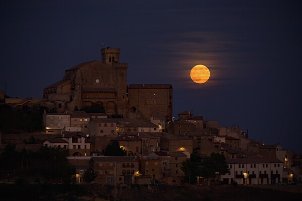 The moon known as blue moon rises behind the small village of Ujue, northern Spain, Wednesday, Aug. 30, 2023. (AP Photo/Alvaro Barrientos)