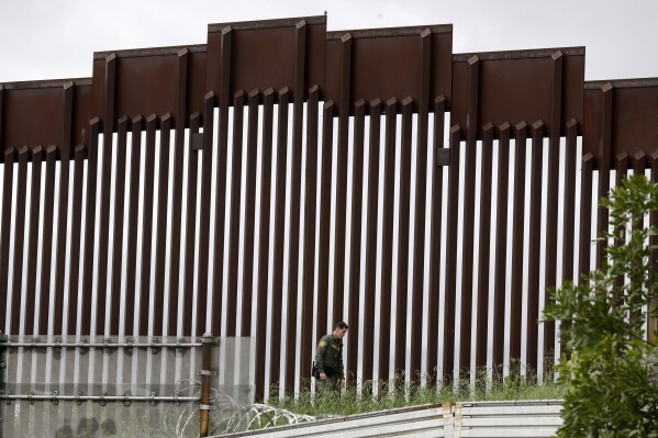 FILE - A Border Patrol agent walks along a border wall separating Tijuana, Mexico, from San Diego, in San Diego, on March 18, 2020. Eleven people were found hurt Saturday, March 2, 2024, after trying to climb over a wall that separates Mexico and the United States and falling on the San Diego side, the latest such injuries since the wall was heightened to deter illegal crossings. (AP Photo/Gregory Bull, File)