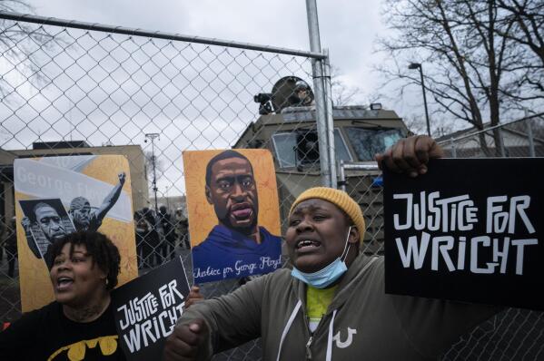 Demonstrators shout along a perimeter fence guarded by law enforcement officers during a protest over Sunday's fatal shooting of Daunte Wright during a traffic stop, outside the Brooklyn Center Police Department, Wednesday, April 14, 2021, in Brooklyn Center, Minn. (AP Photo/John Minchillo)