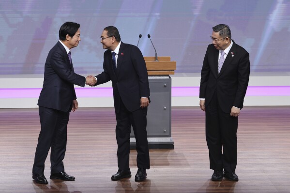 Taiwan President and Democratic Progressive Party presidential candidate William Lai, from left, shakes hands with Taiwan's Nationalist Party presidential candidate Hou Yu-ih while Taiwan's Taiwan People's Party (TPP) presidential candidate Ko Wen-je stands by before the presidential debates at Taiwan Public Television Service in Taipei, Taiwan, Saturday, Dec. 30, 2023. Taiwan will hold its presidential election on Jan. 13, 2024. (AP Photo/Pei Chen, Pool)