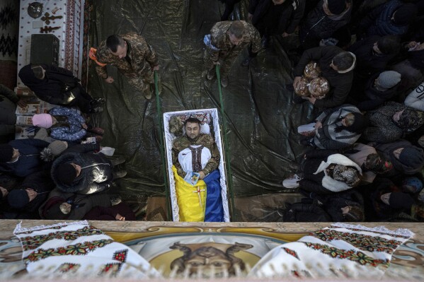 Ukrainian servicemen carry the coffin of Ukrainian army officer Vasyl Medviychuk at a church in the Carpathian mountains in Krasnyk village, Ukraine, Friday, Dec. 29, 2023. (AP Photo/Evgeniy Maloletka)