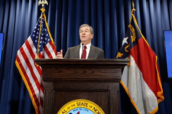 FILE - Gov. Roy Cooper talks about what is in his budget adjustment bill during a press conference in Raleigh, N.C., Wednesday, April 24, 2024. North Carolina officials downgraded a projected state revenue surplus through mid-2025 by $430 million on Friday, May 10, 2024, citing lower than anticipated April 15 individual income tax payments due to recent business tax changes. Still, the state expects nearly $1 billion more to enter its coffers. (Ethan Hyman/The News & Observer via AP, File)
