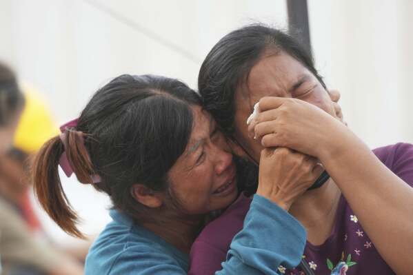 Women cry as they wait for news as rescue work is underway at the site of an under construction high-rise building that collapsed after an earthquake in Bangkok, Thailand, Sunday, March 30, 2025. (AP Photo/Sakchai Lalit)
