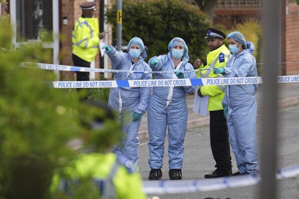 Forensics officers gesture near the scene of an attack in Hainault, north east London, Tuesday April 30, 2024. A man wielding a sword attacked members of the public and police officers in a east London suburb, killing a 13-year-old boy and injuring four others, authorities said Tuesday. The man was arrested at the scene, police said. Chief Supt. Stuart Bell said the incident is not being treated as terror-related or a “targeted attack.” (Jordan Pettitt/PA via AP)
