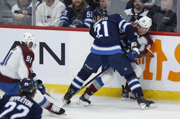 Winnipeg Jets' Dominic Toninato (21) checks Colorado Avalanche's Andre Burakovsky (95) during second-period NHL hockey game action in Winnipeg, Manitoba, Sunday, April 24, 2022. (John Woods/The Canadian Press via AP)