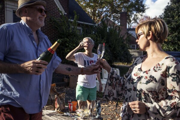 Damon Akins, from left, Colleen Trimble and Kathryn Shields drink champagne at a celebration for President-elect Joe Biden in Greensboro, N.C., on Saturday, Nov. 7, 2020. (Khadejeh Nikouyeh/News & Record via AP)