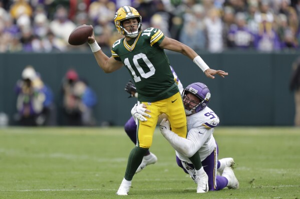 Green Bay Packers quarterback Jordan Love (10) passes the football Minnesota Vikings defensive tackle Harrison Phillips (97) attempts to tackle during the second half of an NFL football game Sunday, Oct. 29, 2023, in Green Bay, Wis. (AP Photo/Matt Ludtke)