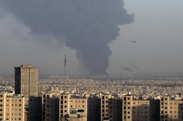 Huge smoke rises up from Tehran's main oil refinery as a plane approaches Mehrabad airport south of Tehran, Iran, Wednesday, June 2, 2021. A massive fire broke out Wednesday night at the oil refinery serving Iran's capital, sending thick plumes of black smoke over Tehran. (AP Photo/Vahid Salemi)