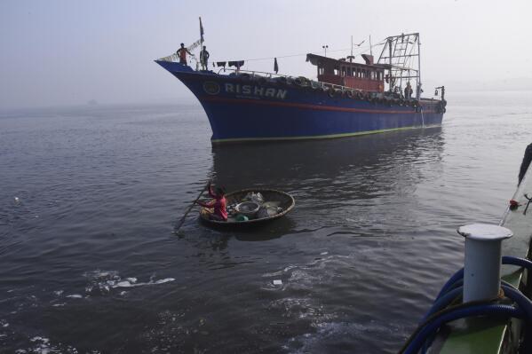 A woman rows a boat in past fisherman on March 3, 2023, in Kochi, Kerala state, India. The India Meteorological Department as well as the state of Kerala have increased infrastructure for cyclone warnings since Cyclone Ockhi in 2017, which killed about 245 fishermen out at sea. (AP Photo/Satheesh AS)