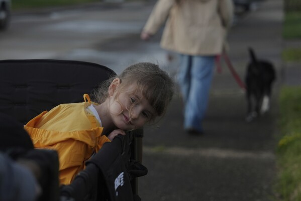 Eliza Ethridge, 5, rides in a wagon during a walk with her family, Thursday, April 10, 2025, in Evansville, Ind. (AP Photo/Joshua A. Bickel)