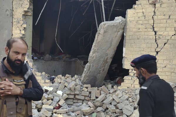 Police officers examine damages on the site of a bombing at a police station on the outskirts of Dera Ismail Khan, Pakistan, Tuesday, Dec. 12, 2023. A suicide bomber detonated his explosive-laden vehicle at a police station's main gate in northwest Pakistan on Tuesday, killing several policemen and wounding more than dozen others, officials said. Some militants also opened fire and a shootout between them and security forces was still ongoing, police officer Kamal Khan said. (AP Photo)