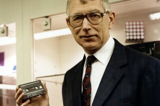 In this photo dated 1988, structural engineer Lou Ottens holding an audio cassette poses for a photo.  The Dutch inventor of the cassette tape, Ottens died Saturday March 6, 2021, at the age of 94, according to an announcement issued by the Philips company. (Philips Company Archives via AP)