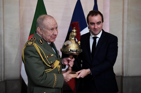Algerian Army chief, Gen. Said Chanegriha, left, gets a present given by French Defense Minister Sebastien Lecornu, Tuesday, Jan.24, 2023 in Paris. Algeria's Defense Ministry said the visit was aimed at strengthening cooperation between the Algerian and French armies and would allow the two sides "to examine questions of common interest." ( Christophe Archambault, Pool via AP)