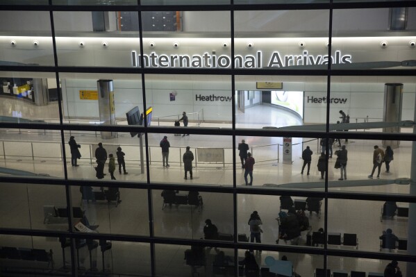 FILE - People in the arrivals area at Heathrow Airport in London, Jan. 26, 2021. The British government says it will grant extensions to several large U.K. airports unable to meet the June 1 deadline to fully install new scanning technology that would have allowed passengers to take two liters (70 ounces) of liquid in their hand luggage — rather than the current paltry 100 milliliters (3.5 ounces). (AP Photo/Matt Dunham, File)