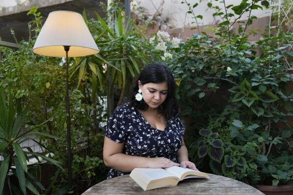 A Lebanese Armenian of Christian heritage, Talar Demirdjian, reads a book as she sits at a coffee shop in Beirut, Lebanon, Saturday, Sept. 2, 2023. The role of sectarian divisions in fueling conflicts in religiously diverse Lebanon is one reason Demirdjian kept her distance from religion. Demirdjian said that when it comes to religion, "I identify as I don't care… I don't even think about it enough to tick a label." (AP Photo/Hussein Malla)