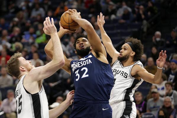 Minnesota Timberwolves center Karl-Anthony Towns (32) shoots between San Antonio Spurs center Jakob Poeltl (25) and guard Derrick White (4) in the first half of an NBA basketball game, Thursday, Nov. 18, 2021, in Minneapolis. (AP Photo/Andy Clayton-King)