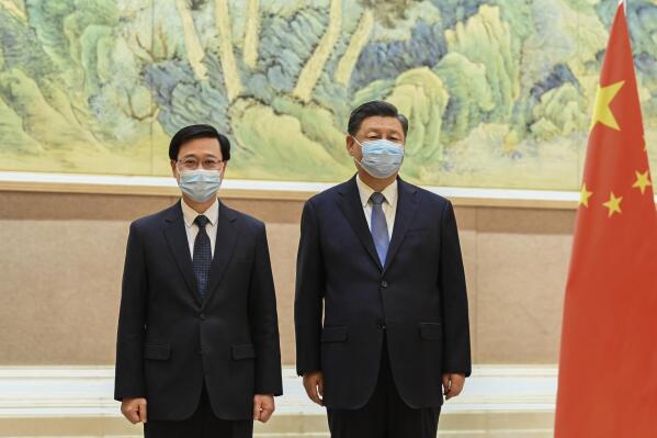 In this photo released by Xinhua News Agency, Chinese President Xi Jinping, right, and Hong Kong Chief Executive-elect John Lee pose for photo before their meeting in Beijing, Monday, May 30, 2022. Hong Kong's next leader, John Lee, has received an official letter of appointment from Beijing a month before he is to take over the leadership of the semi-autonomous city. (Li Xueren/Xinhua via AP)