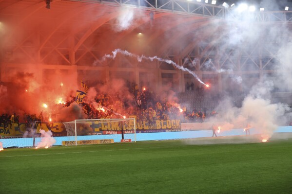 Fans throw flares in the pitch before the Cyprus' cup soccer match between AEL and Apollon at Alpha Mega stadium in Kolossi near Limassol, Cyprus, Wednesday, Jan. 24, 2024. A key Cyprus Cup battle between perennial Limassol rivals Apollon and AEL has been called off after a number of fans invaded the pitch and hurled flares at each other prior to the start of the match. (AP Photo)