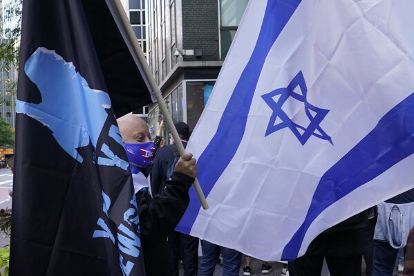 A protester holds a flag as he stands beside another bearing an Israeli flag while joining a group of protesters outside the offices of New York Gov. Andrew Cuomo, Thursday, Oct. 15, 2020, in New York. Three Rockland County Jewish congregations have filed a lawsuit accusing Gov. Andrew Cuomo of engaging in a streak of anti-Semitic discrimination with a crackdown on religious gatherings. The Manhattan federal court lawsuit filed Wednesday says Cuomo has made numerous discriminatory statements about the Jewish Orthodox community.  (AP Photo/Kathy Willens)