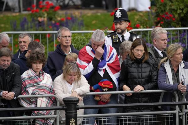 Members of the public, one of them holding a Paddington Bear toy, outside Buckingham Palace wait to watch Queen Elizabeth II funeral procession, in central London on Monday, Sept. 19, 2022. (AP Photo/Christophe Ena, Pool)