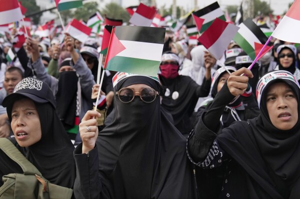 Muslim women wave Palestinian and Indonesian flags during a rally supporting the Palestinians in Jakarta, Indonesia, Sunday, Oct. 15, 2023. (AP Photo/Dita Alangkara)