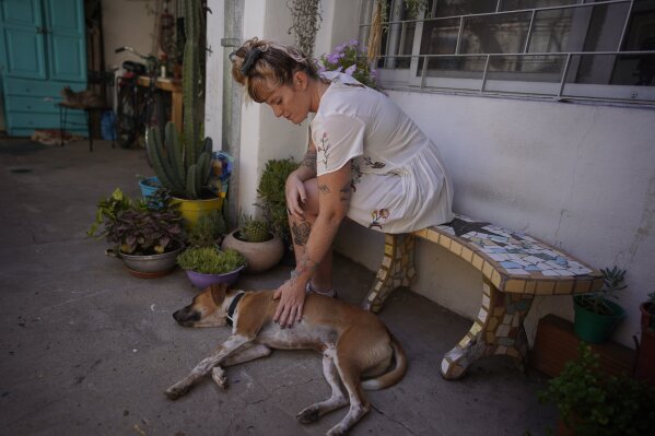 Tamara Grinberg, 32, pets her dog at her home in San Martin, Buenos Aires province, Argentina, Friday, Jan. 22, 2021. Grinberg who had a clandestine abortion in 2012 said very few people helped her. “Today there are many more support networks ... and the decision is respected. When I did it, no one respected my decision.". (AP Photo/Victor R. Caivano)