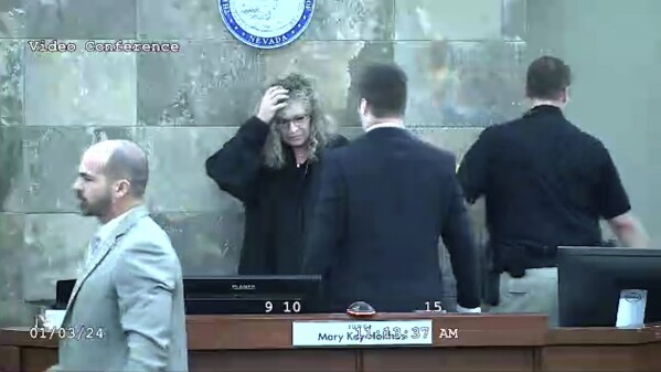 In this image from video provided by the Clark County District Court, Judge Mary Kay Holthus is seen cradling her head after a defendant launched over her desk during his sentencing in a felony battery case, Wednesday, Jan. 3, 2024 in Las Vegas. Redden, who was captured in courtroom video leaping over a judge's bench and attacking her, touching off a bloody brawl, is scheduled to appear before her again Monday morning, Jan. 8, 2024. (Clark County District Court via AP)