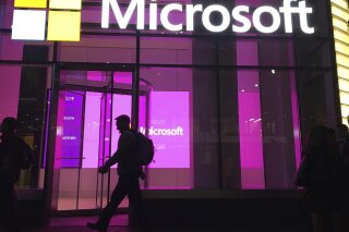 FILE - In this Nov. 10, 2016, file photo, people walk past a Microsoft office in New York. China-based government hackers have exploited a bug in Microsoft's email server software to target U.S. organizations, the company said Tuesday, March 2, 2021. (AP Photo/Swayne B. Hall, File)