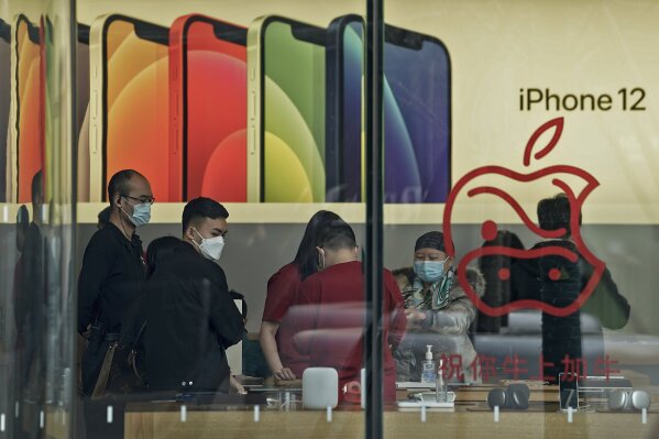 People wearing face masks to help curb the spread of the coronavirus look at iPad devices at an Apple store at the capital city's popular shopping mall in Beijing on Wednesday, Feb. 24, 2021. China’s commerce minister appealed to Washington for “join efforts” revive trade but gave no indication Wednesday when tariff war talks might resume or whether Beijing might offer concessions. (AP Photo/Andy Wong)
