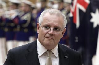 FILE - In this Nov. 17, 2020, file photo, Australian Prime Minister Scott Morrison reviews an honor guard during a ceremony ahead of a meeting at Japanese Prime Minister Yoshihide Suga's official residence in Tokyo. Morrison said Monday, Nov. 30, 2020, a tweet by a Chinese official which shows a fake image of an Australian soldier appearing to slit a child's throat is “truly repugnant." (Kiyoshi Ota/Pool Photo via AP, File)