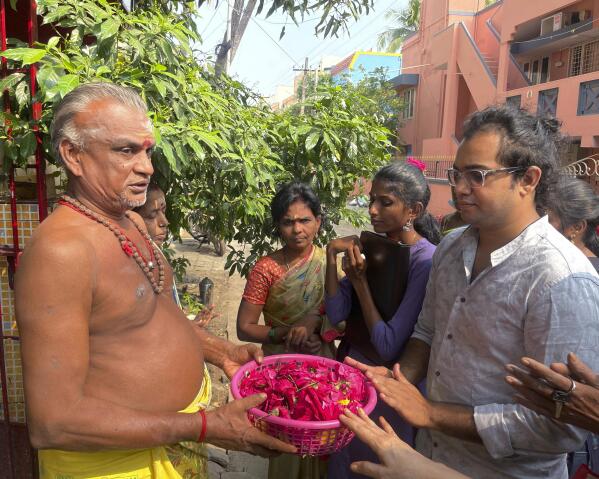 Arjun Viswanathan places his hands on a basket of flowers to be offered to the Hindu deity Ganesh at the Sri Lakshmi Visa Ganapathy Temple on Nov. 28, 2022, in Chennai, a city on the southern coast of India. These "visa temples" can be found in almost any Indian city with a U.S. consulate. They have surged in popularity because of a belief popularized on social media that those who pray there will not just get their visa, but will enjoy a smooth, stress-free path to getting it. (AP Photo/Deepa Bharath)